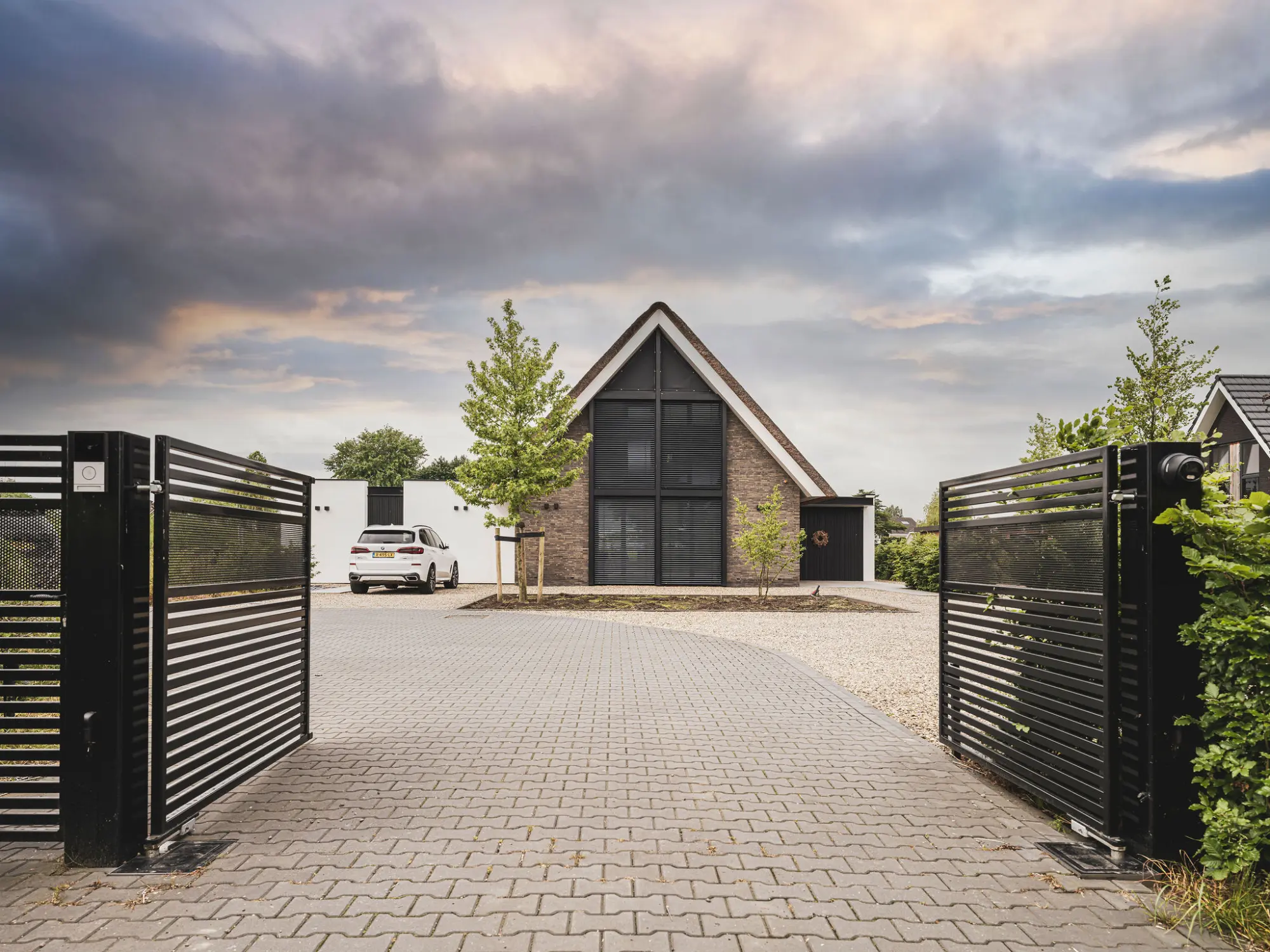 Hedendaagse woning, met rieten kap, gemetselde muren, grote raampartijen, aluminium lamellen, architectuur van Bongers architecten in Oud Alblas en aannemer Buitenhuis Villabouw in Alblasserdam, aluminium toegangspoort en hekwerk