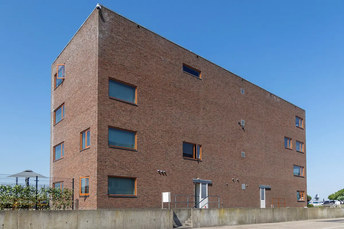 Strak vormgegeven bedrijfsgebouw met robuuste bakstenen gevel en minimalistische raampartijen &ndash; Bongers Architecten