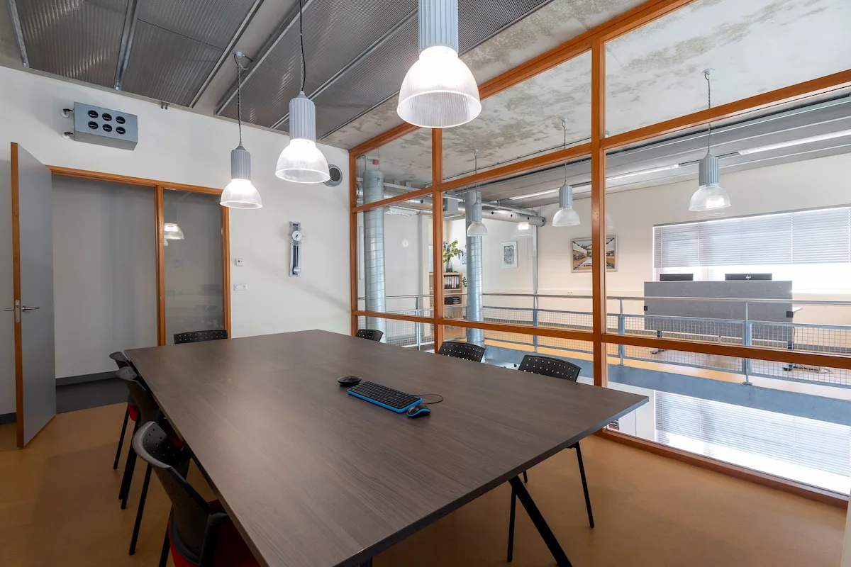 Vergaderruimte met glazen binnenwanden, houten kozijnen en industri&euml;le plafonds &ndash; interieurontwerp Bongers Architecten bij Kleijn Transport