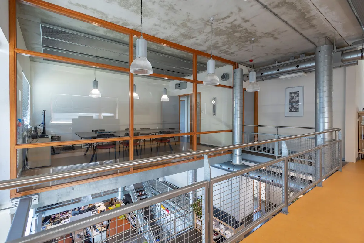 Industri&euml;le kantoorverdieping met zicht op vergaderruimte, stalen balustrade en zichtbare installaties &ndash; Kleijn Transport Alblasserdam.