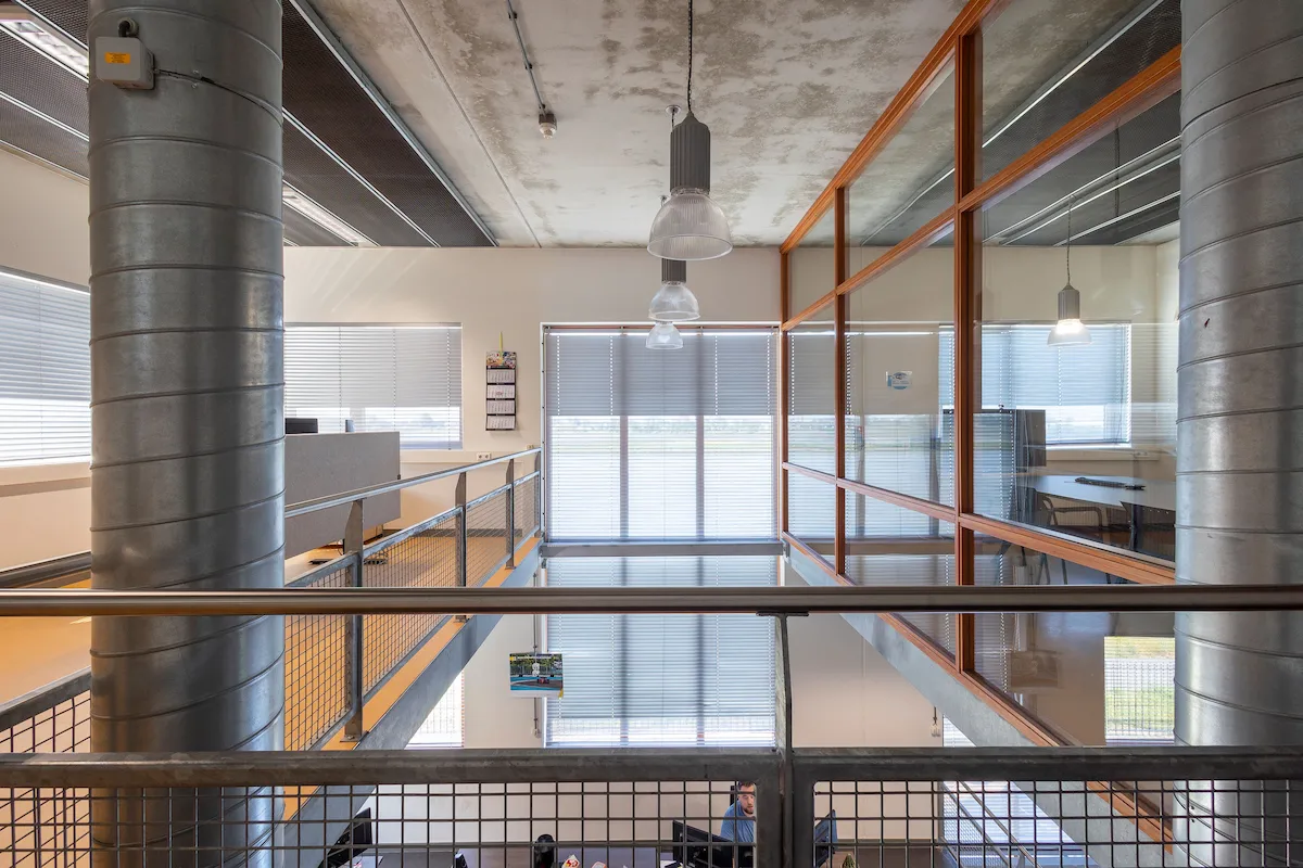 Kantoorinterieur met zichtbare installaties, glazen wanden en stalen balustrade &ndash; industri&euml;le look bij Kleijn Transport Alblasserdam.