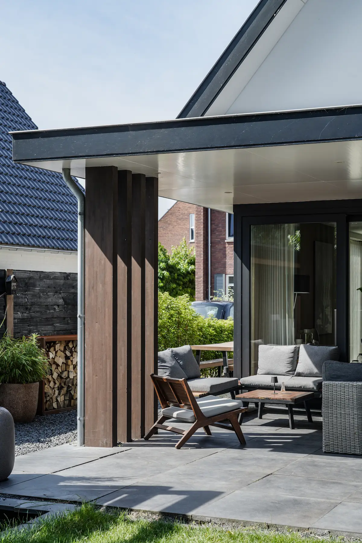 Detail van een overdekt terras met houten kolom, strakke dakrand en beschutte zitplek bij een moderne woning in Hendrik-Ido-Ambacht.