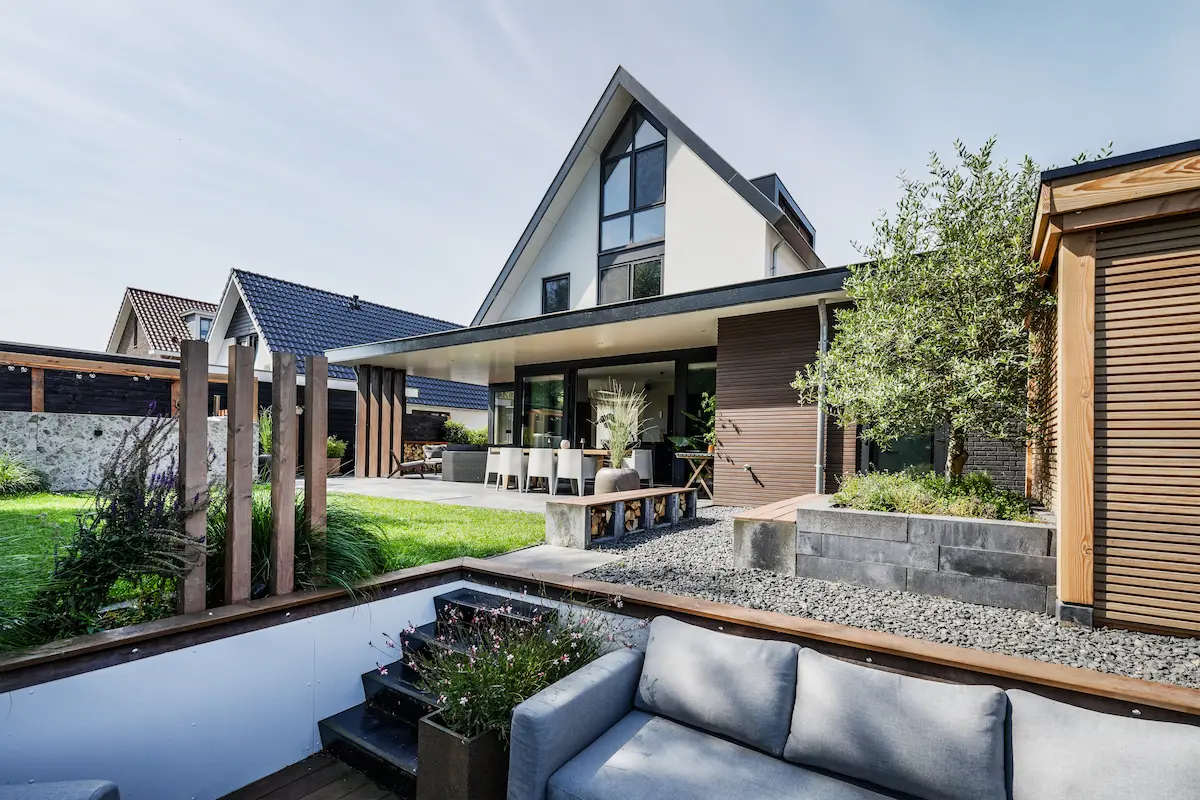 Moderne woning in Hendrik-Ido-Ambacht met witte kap, houten aanbouw, overdekt terras en een verdiept loungegedeelte in de tuin.