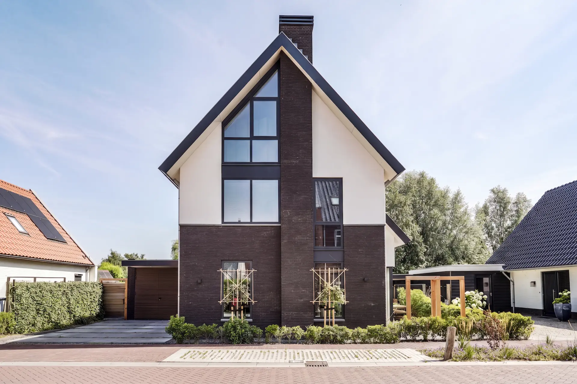 Voorgevel van een moderne woning in Hendrik-Ido-Ambacht met steile kap, donkere baksteen, witte gevelvlakken en hoge glaspartijen.