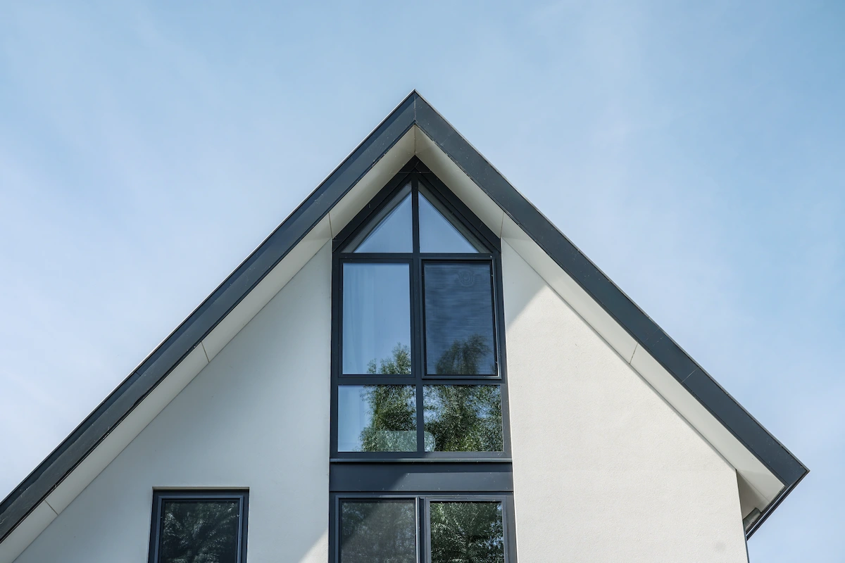 Detail van een moderne woning in Hendrik-Ido-Ambacht met witte topgevel, steile kap en hoge donkere glaspui voor extra daglicht.
