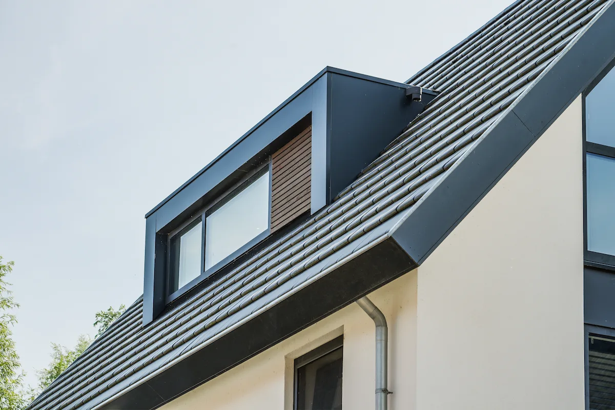 Moderne dakkapel op een steile pannenkap met donker kader, houten gevelaccent en strakke detaillering bij een woning in Hendrik-Ido-Ambacht.