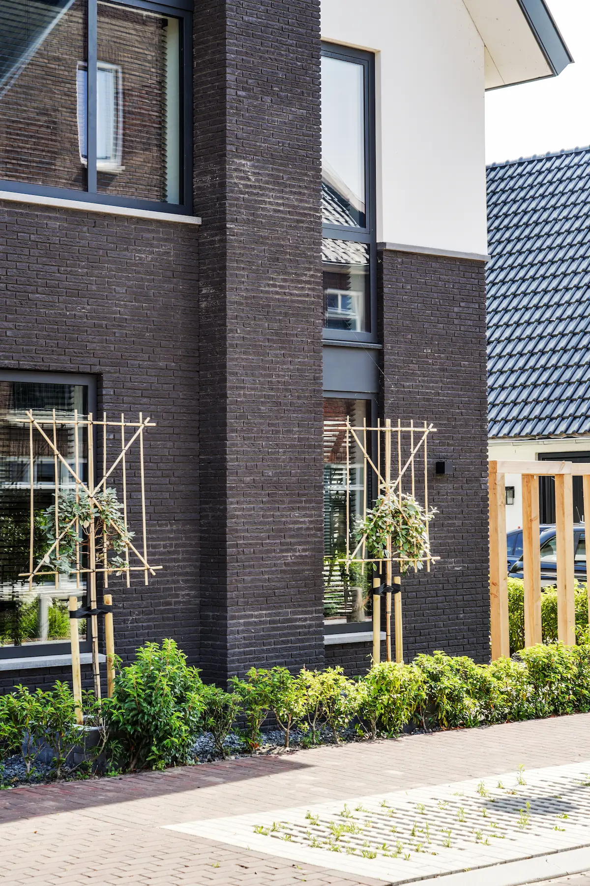 Detail van een moderne woning in Hendrik-Ido-Ambacht met donker metselwerk, witte gevelvlakken en hoge verticale ramen.