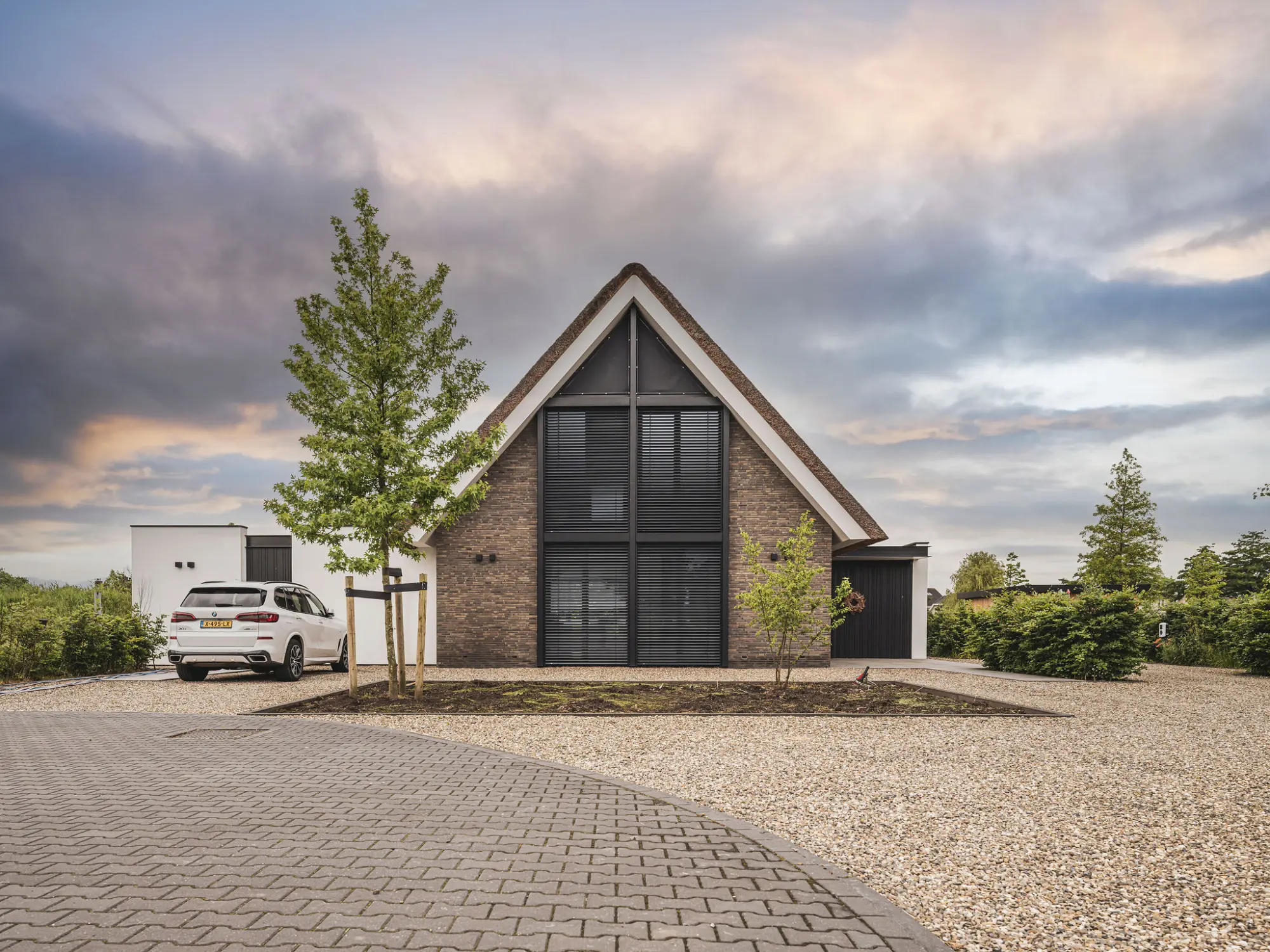 Hedendaagse woning, met rieten kap, gemetselde muren, grote raampartijen, aluminium lamellen, architectuur van Bongers architecten in Oud Alblas en aannemer Buitenhuis Villabouw in Alblasserdam