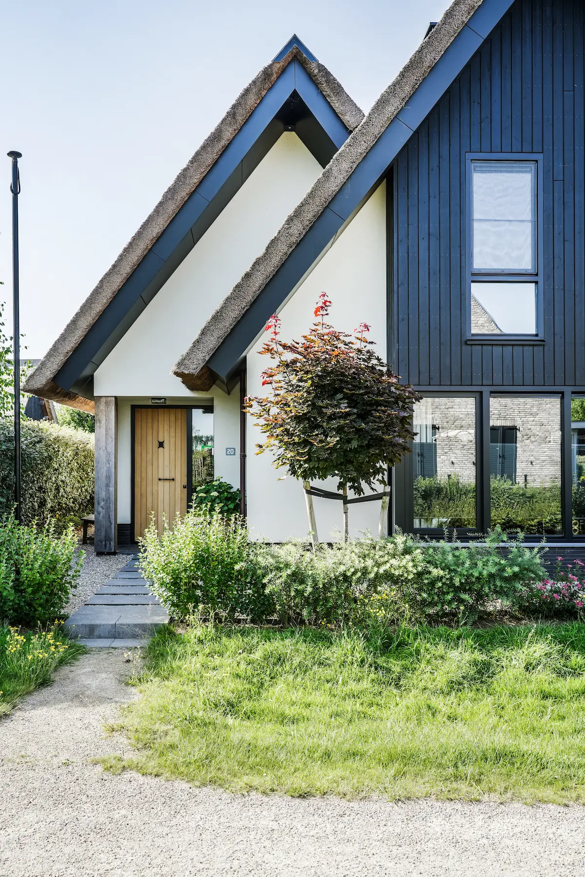 Moderne woning met rieten kap, donkere houten gevelbekleding, wit stucwerk en grote ramen, ontworpen door architect in Oud-Alblas.