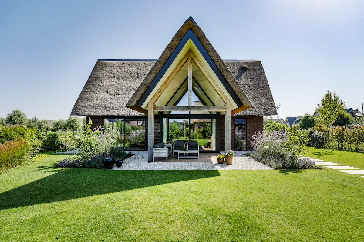 Moderne villa met rieten kap, glazen achtergevel en houten spanten, gericht op licht en tuinzicht, ontworpen door architect Drechtsteden.