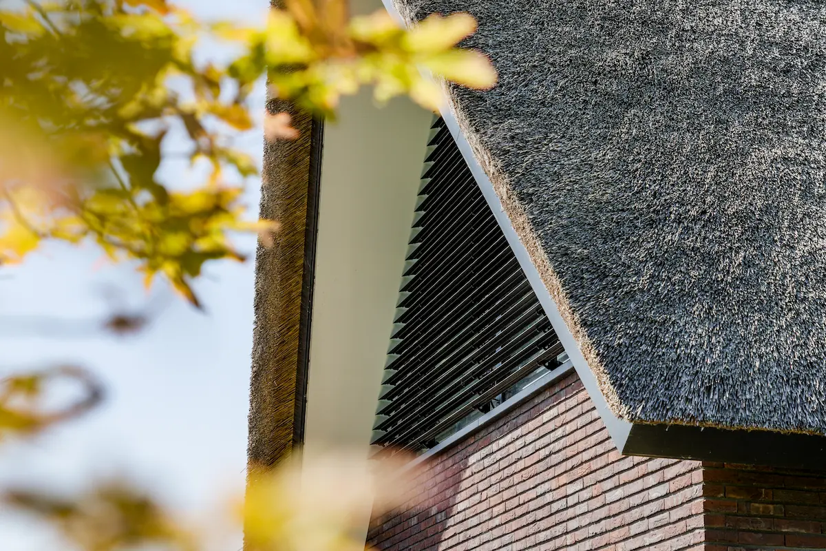 Geveldetail van een moderne villa met rieten kap, donkere baksteen en zwarte lamellen, ontworpen door architect in Oud-Alblas.