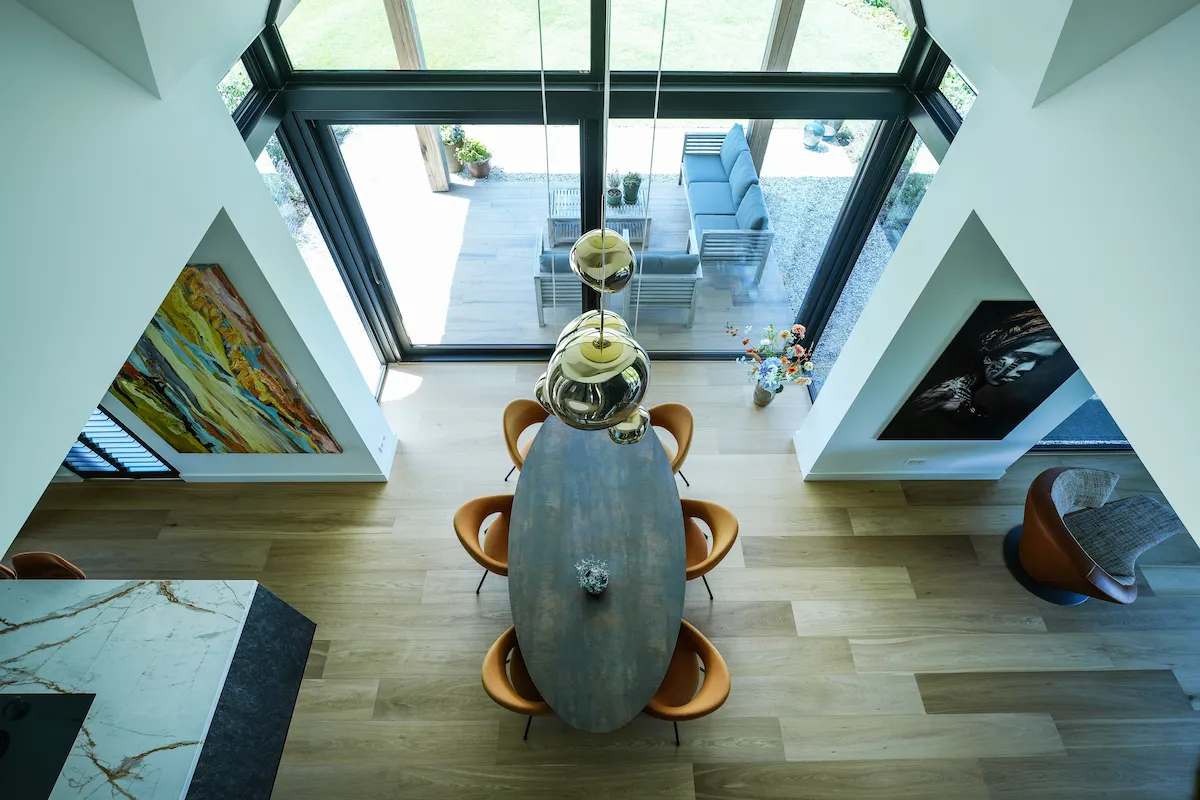 Zicht vanuit de vide op de eethoek, hoge glasgevel en open zichtlijnen in een moderne woning met architectuur van Bongers Architecten.