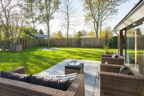 Zonnig terras met loungeset en ruime tuin bij recreatiewoning &ndash; architect woningontwerp met focus op buitenleven en lichtinval.