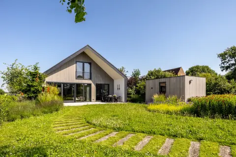 Moderne villa met houten gevel, grote glaspartijen en een groene tuin, duurzaam ontworpen met strakke architectuur door architect in Oud-Alblas.