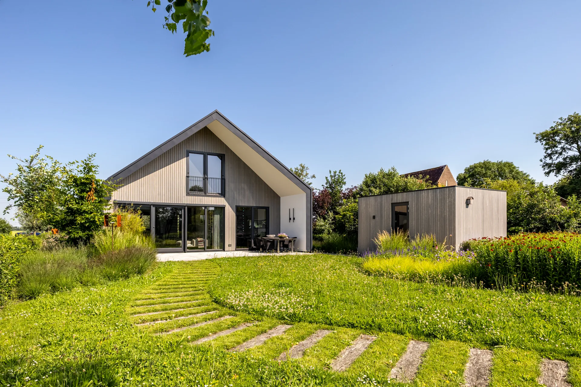 Moderne villa met houten gevel, grote glaspartijen en een groene tuin, duurzaam ontworpen met strakke architectuur door architect in Oud-Alblas.
