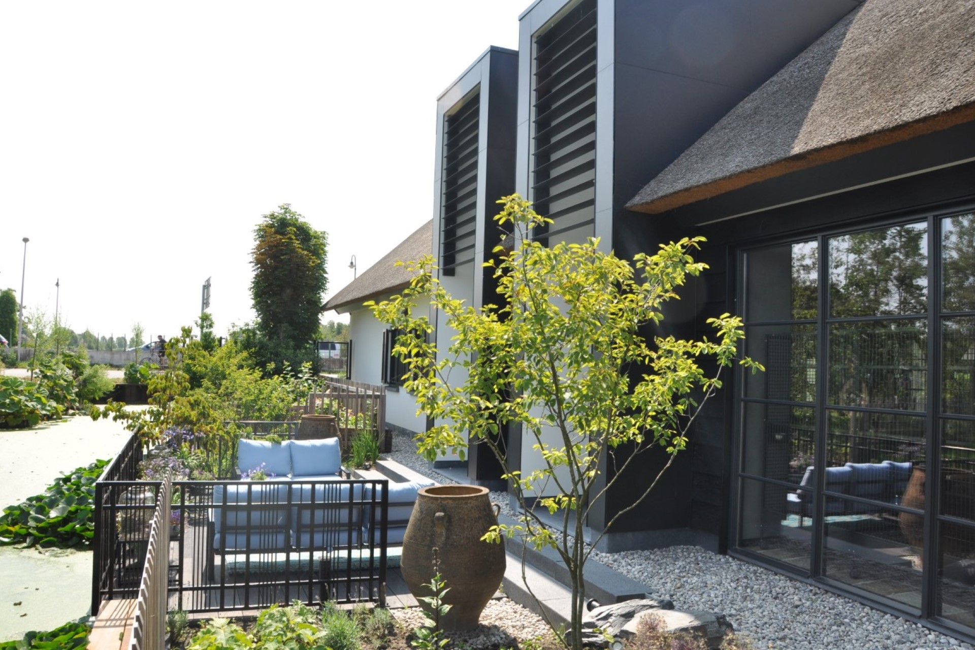 Moderne verbouwing van woonboerderij met stalen puien, rieten dak en zitplek aan het water &ndash; architect Oud-Alblas voor duurzaam en functioneel ontwerp
